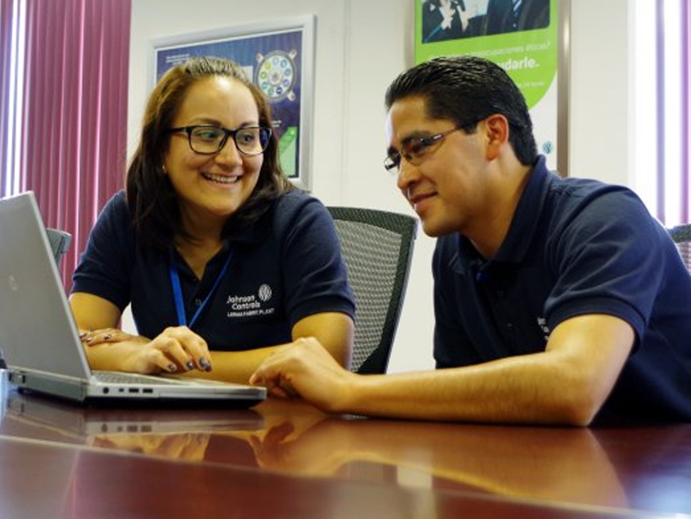 Two Johnson Controls employees sitting at a conference table with a laptop open in front of them