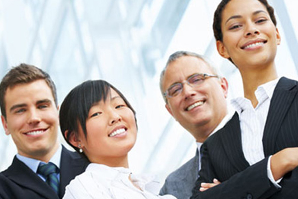 Upwards shot of four business people looking down at the camera and smiling