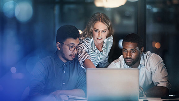 Three young professionals discussing work over a laptop 